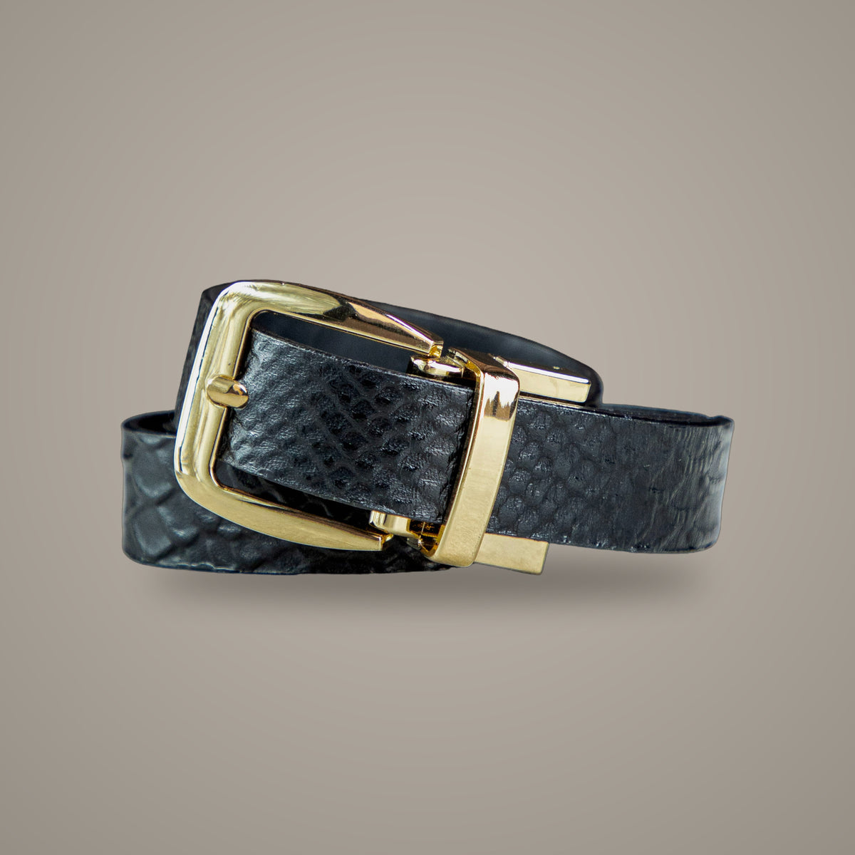 Cinturón Dama Luxury Negro en cuero grabado con hebilla dorada, sobre fondo greige de estudio
